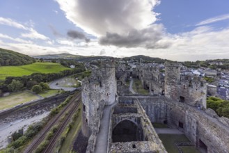 Conwy Castle, medieval castle with towers and surrounding town in a green landscape under a cloudy