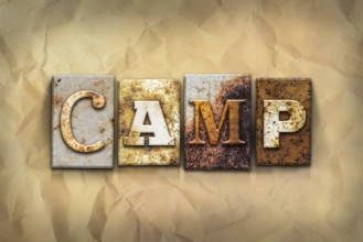 The word CAMP written in rusty metal letterpress type on a crumbled aged paper background