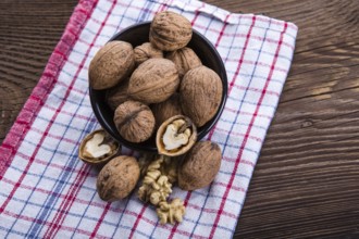 Walnut kernels and whole walnuts on old wooden table and dish towel