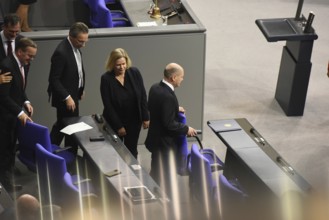 Federal Chancellor Olaf Scholz (SPD) holds on to the back of his chair while some of his ministers