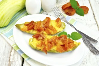 Young zucchini baked in a flavored sauce with dried apricot, cream and cheese in a bowl on a towel
