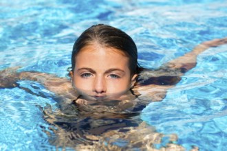 Beautiful blue eyes kid girl at the pool with face in water surface