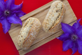 Fragrant breakfast - Two wheat bread and clematis flower on wooden desk