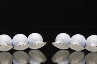 Six spoons and golf balls on a black glass desk