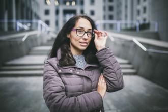 Portrait beautiful young business woman brunette in jacket and jumper stands on background office
