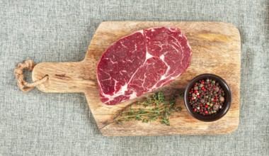 Steak made from fresh beef, with herbs and various spices, on a wooden chopping board, ready to