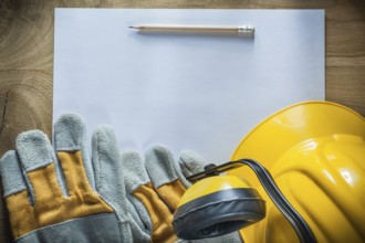 Pencil paper protective gloves hard hat earmuffs on wooden board
