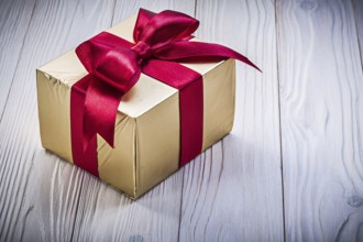 Present box in glittery paper on wooden board holidays concept