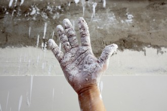 Astist plastering man hand with white dried cracked plaster texture in fingers