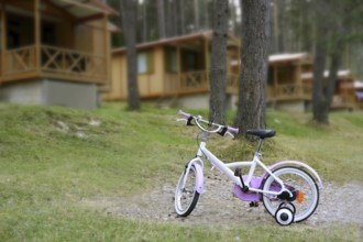 Chidren pink bicycle in wooden cabin mountain pine camping Pyrenees