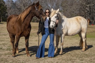 A beautiful brunette cowgirl poses with her horse before a ride in the countryside