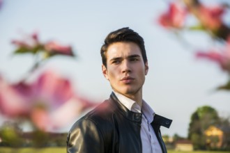 Good looking male model at couuntryside, among flowers, enjoying nature