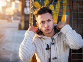 One handsome young man in urban setting in moden city, standing, wearing black coat and scarf in