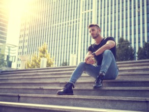 One handsome young man in urban setting in European city, wearing jeans and black t-shirt