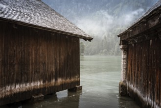 Scenic view of wooden cottages in Konigssee lake a misty summer day in Konigssee lake a misty