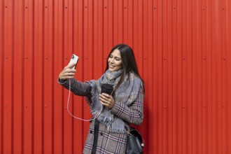 Young woman designer making selfie photo on red background