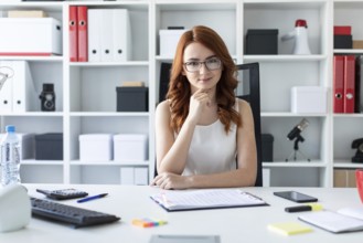 A red-haired young girl with glasses, a white blouse and a red skirt is working in the office.