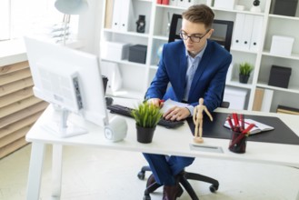 A handsome young man with glasses, a blue suit and a light shirt is working in the office. photo