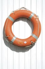 View of an orange-coloured life buoy or a rescue device on a white fence