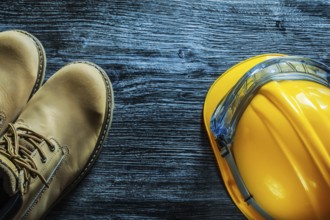 Safety boots building helmet goggles on vintage wooden board