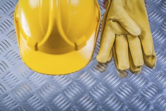 Protective leather gloves hard hat on corrugated metal background construction concept