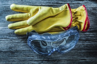 Protective leather gloves glasses on wooden board