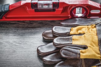 Construction level pair of safety gloves on wooden board