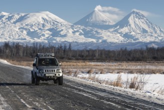 Japanese Sport Utility Vehicle Suzuki Jimny driving along road on background beautiful winter