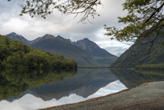 Tranquil lake Gunn in Fiordland National Park, landscape reflecting on the water surface, South