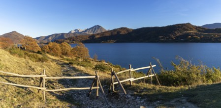 A wooden fence and hiking trail on the banks of Campotosto Lake in the mountains of Abruzzo in