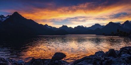 Beautiful picturesque autumn landscape of majestic rocky mountain peaks covered with snow. The lake