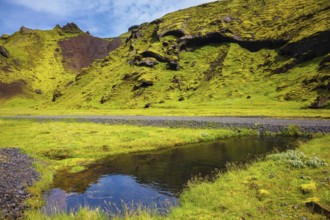 Picturesque basalt hills overgrown green grass and moss. On bottom of canyon many streams flow.