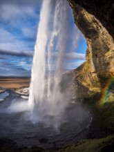 Seljalandsfoss, a majestic and powerful waterfall in Iceland in a sunny spring day with a raibow