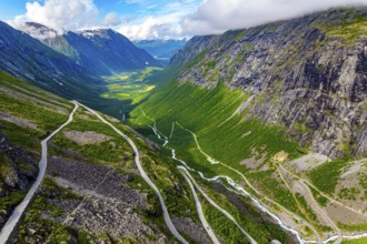 The serpentine road meanders on the green slopes of the canyon. Filming from a drone. Summer trip