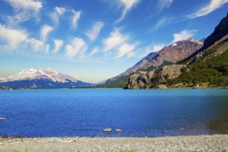 Huge lake with azure water rocky beach by the lake. Patagonia. Pampas surround snow-capped