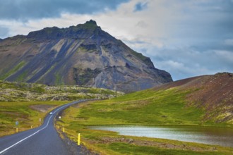 The road passes through the picturesque landscape in the mountains and lakes. Cloud Iceland in the