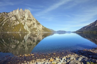 The concept of exotic and extreme tourism. The mirror water of the lake reflects sharp peaks and