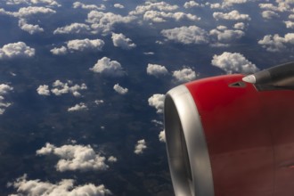 A colour landscape image looking out through airplane window showing land, cloud and sky