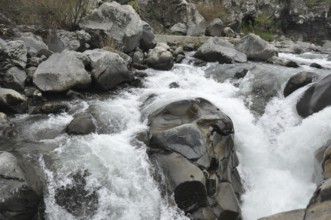 Whitewater rapids swirling around large rocks in a river, The Alcantara Park is located on the