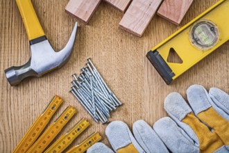 Set of tools claw hammer stack of nails safety gloves construction level wooden meter planks on