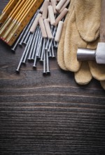 Wooden meter heap of dowels claw hammer brown protective gloves and metal nails on vintage wood