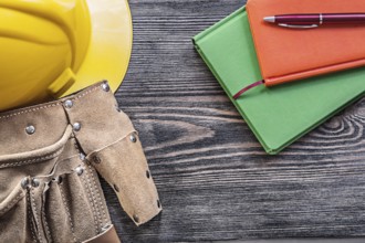 Collection of tool belt notepads pen building helmet on wooden board construction concept