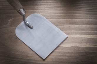 Steel glossy bricklaying trowel on wood board construction concept