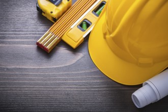 Tape-line blueprints construction level hard hat and wooden meter on vintage wood board maintenance