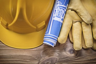 Blue blueprint hard hat protective gloves on wooden board construction concept