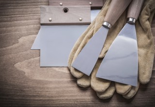 Two paint scrapers putty knifes working gloves