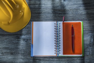 Spiral notepad pen building helmet on wooden board