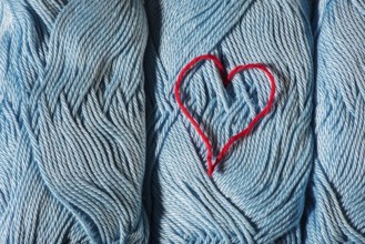 Knitted red heart on blue balls of yarn