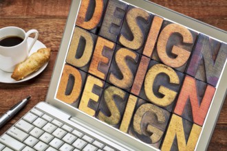 Design - word abstract in vintage wood letterpress block types on a laptop screen with a cup of