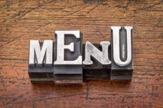 Menu word in vintage metal type printing blocks over grunge wood